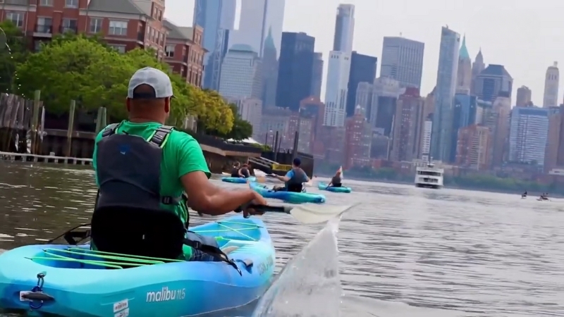 A Group of Kayakers Paddling Along the Waterfront with The Manhattan Skyline in The Background