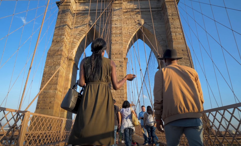 Man and a woman walking across the Brooklyn Bridge