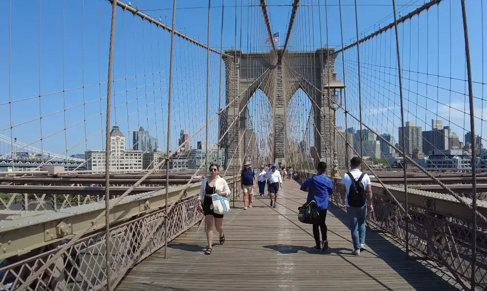 Pedestrians traverse the Brooklyn Bridge, enjoying the city views