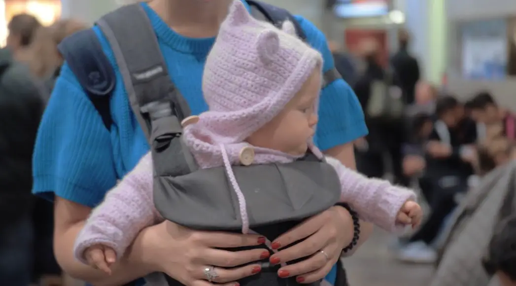 A mother carries her baby in a carrier