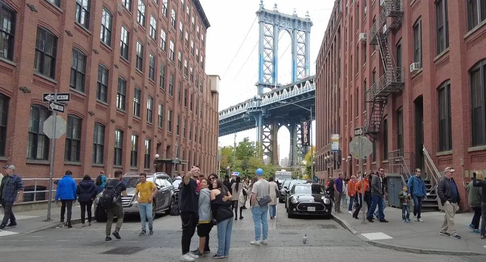 A bustling street scene in New York City, with the Manhattan Bridge towering overhead