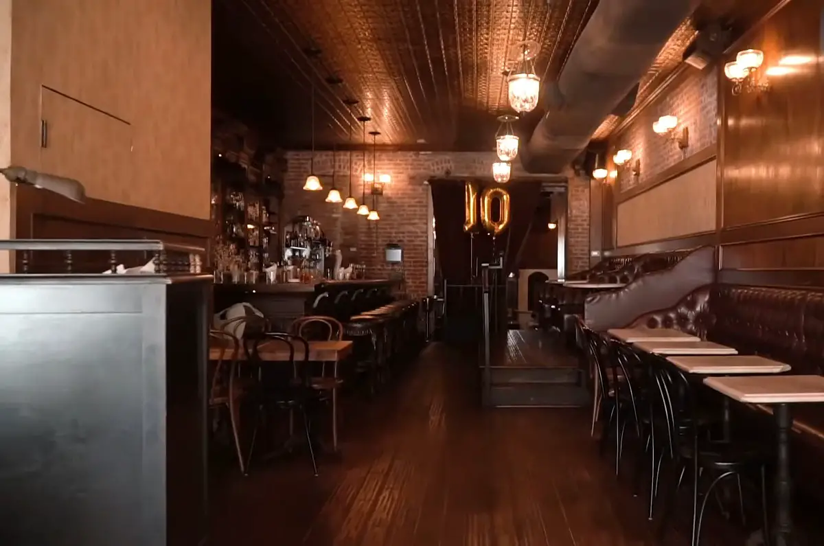 A vintage-style cocktail bar with a long wooden counter