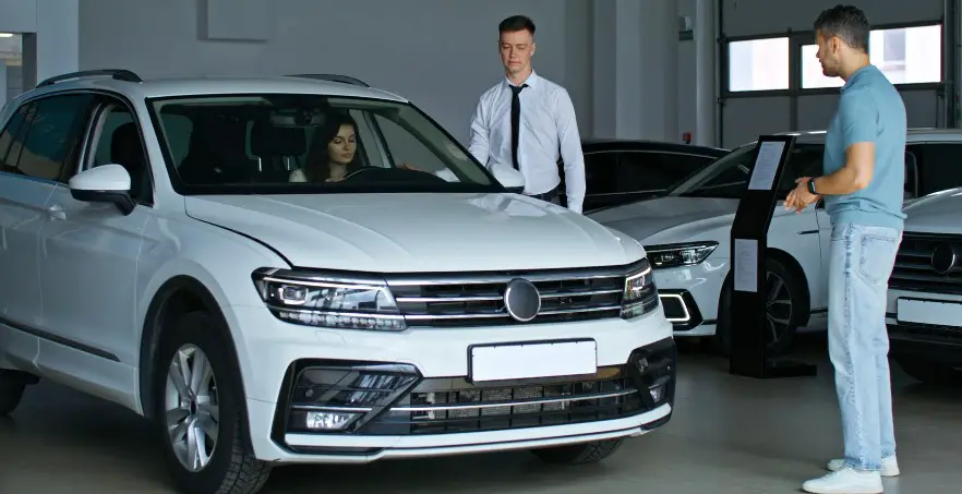 A gleaming white SUV, a potential purchase, awaits. A salesperson guides the customer through the details