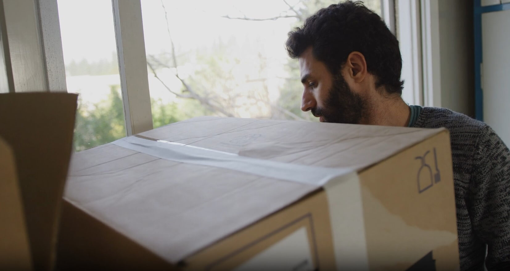 A man meticulously carries a large cardboard box