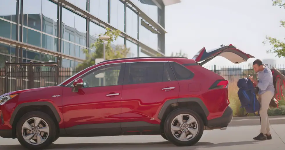 A man loads his backpack into a stylish red crossover