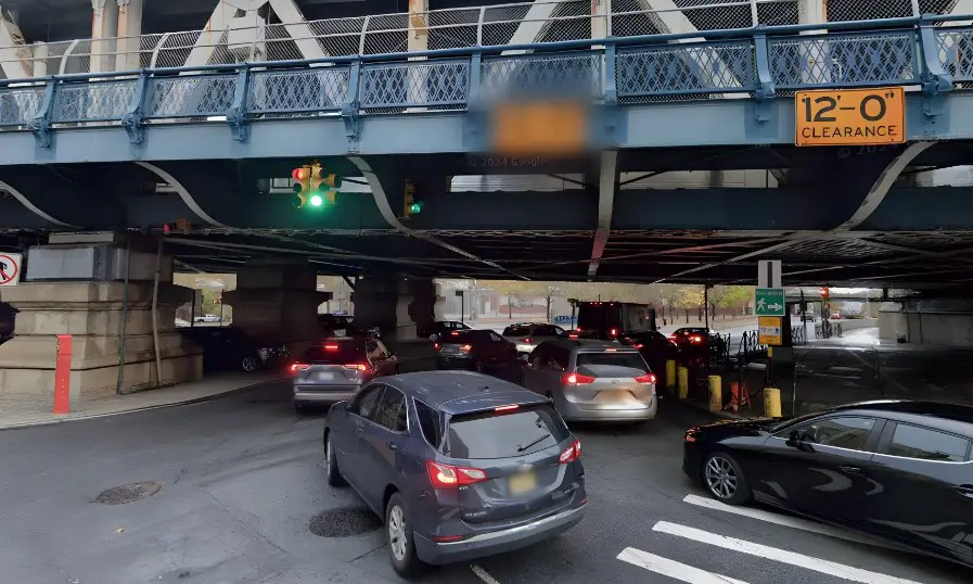 Traffic flows beneath a steel bridge, navigating the 12-foot clearance