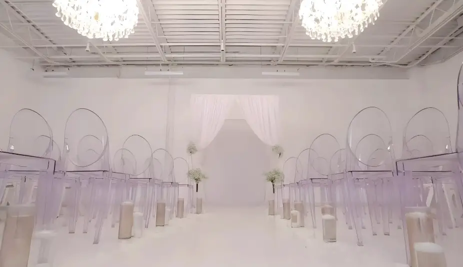 A pristine white space, adorned with clear chairs and a soft, sheer backdrop