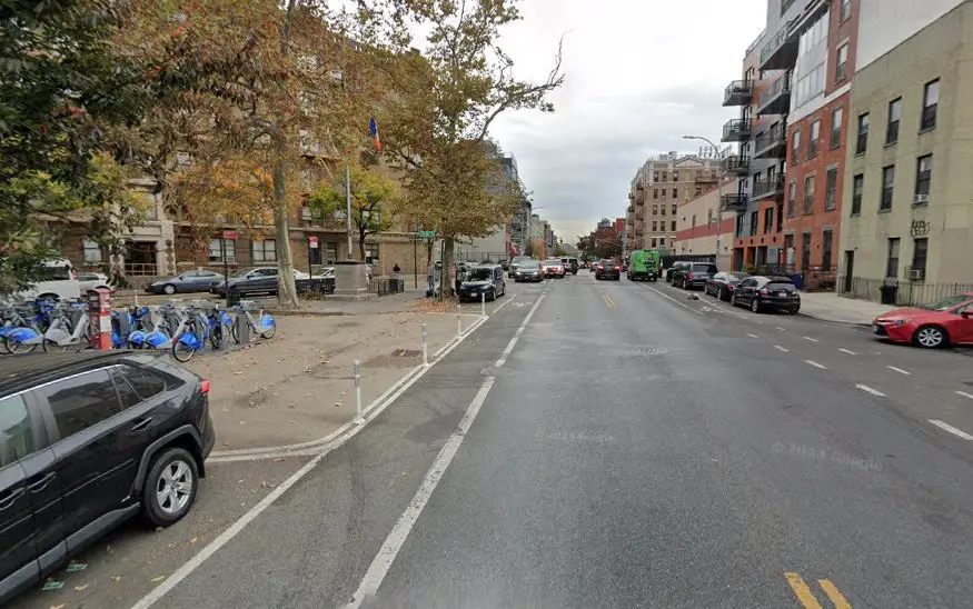 Urban street scene, showing a city block with parked cars and bicycles