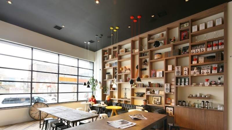 Cozy and modern cafe interior with high shelves, stylish lighting, and a mix of seating arrangements